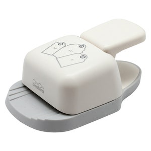 May include: White and grey paper punch with a handle. The punch is designed to create three different sized tags. The punch is labelled "brabbra".