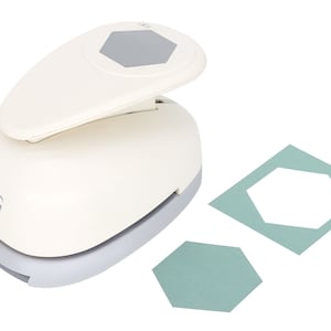 May include: White paper punch with a gray hexagon shape. The punch is on a white background with two hexagon shapes punched out of green paper.
