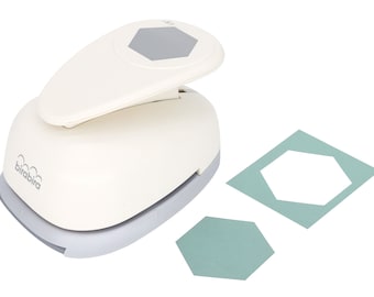 May include: White paper punch with a gray hexagon shape. The punch is on a white background with two hexagon shapes punched out of green paper.