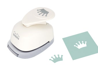 May include: White paper punch with a gray crown design on the top. The punch is on a white background. A small, light blue paper crown is punched out and a larger light blue paper crown is punched out on a light blue square.
