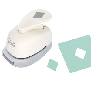May include: A white paper punch with a grey base, featuring a diamond-shaped cutout. The punch is shown next to a light green piece of paper with a diamond-shaped hole punched out.