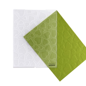 May include: A clear plastic sheet with a pattern of white hearts, layered over a green sheet with a raised pattern of hearts. The green sheet has the word "birabira" printed on it.