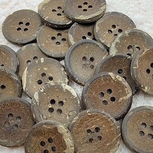 May include: A collection of round, brown coconut buttons with four holes each. The buttons have a natural, textured appearance with lighter, beige-colored markings. These buttons are suitable for sewing and craft projects.