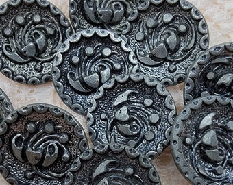 May include: Ten silver-toned buttons with a decorative floral design. The buttons have a scalloped edge and a raised design.