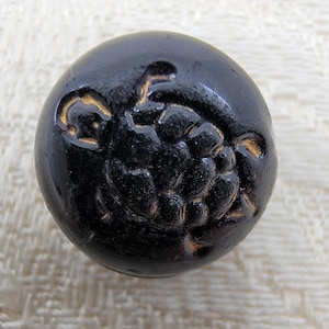 May include: Black round bead with a gold-colored turtle design.
