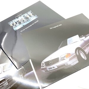 May include: A black and white brochure with a silver Mercedes-Benz 500 SL convertible on the front. The text on the brochure reads "Die Legende lebt" and "500 SL".