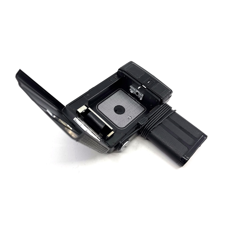 May include: A black and silver camera with the back open, revealing the film compartment and battery slot.