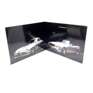 May include: A black and white image of two Mercedes-Benz cars. The car on the left is a silver 1950s model, and the car on the right is a silver 1990s model. The text "Die Legende lebt" is visible on the right side of the image.