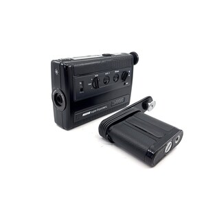 May include: A black vintage Beaulieu Super 8 Pocket L film camera with a detachable viewfinder. The camera has a built-in microphone and a zoom lens.
