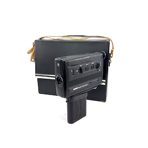 May include: A black Super 8-pocket L video camera with a built-in microphone and zoom lens. The camera is in a black carrying case with a brown leather strap.