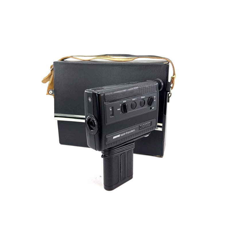 May include: A black Super 8-pocket L video camera with a built-in microphone and zoom lens. The camera is in a black carrying case with a brown leather strap.