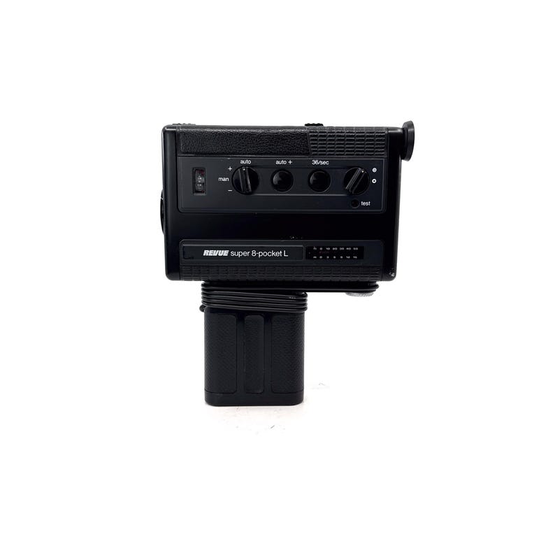 May include: A black Revue super 8-pocket L film camera with a built-in microphone and a zoom lens. The camera has a variety of controls, including a power switch, a zoom control, and a focus ring.