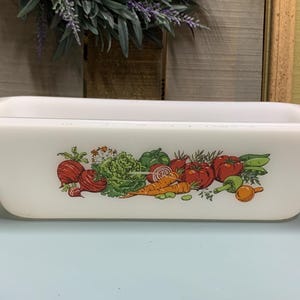 Może przedstawiać: Biała ceramiczna forma do pieczenia z kolorowym wzorem warzyw. Wzór przedstawia czerwone pomidory, zielone papryki, marchewki i cebule.