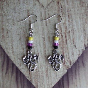 May include: A pair of silver dragon earrings with yellow, white, purple, and black beads.