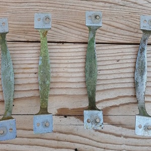 May include: Four vintage metal door handles with a weathered, green patina finish. The handles are rectangular with rounded edges and have two holes for mounting.