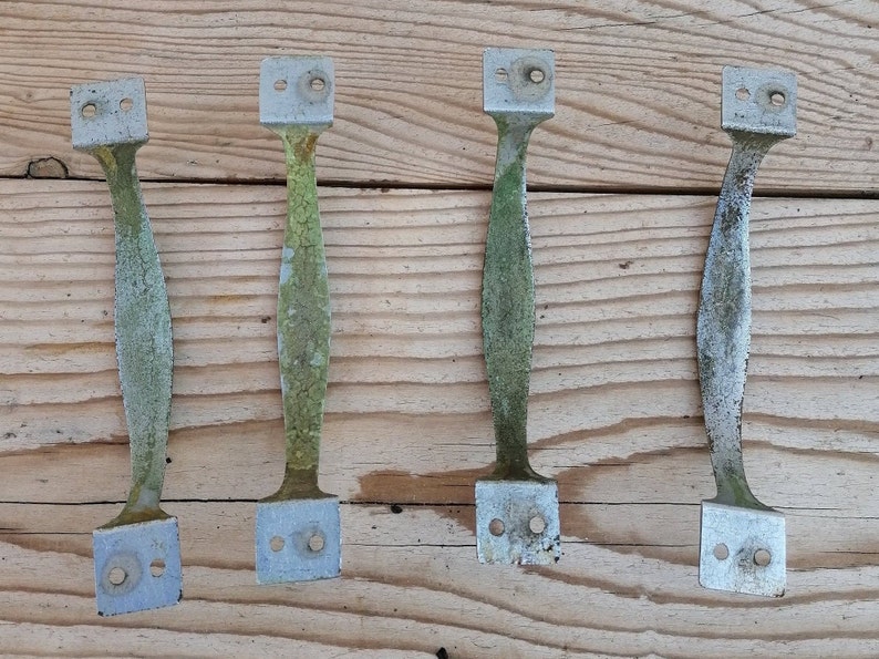 May include: Four vintage metal door handles with a weathered, green patina finish. The handles are rectangular with rounded edges and have two holes for mounting.