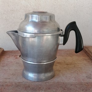 Pode incluir: Uma cafeteira de espresso de alumínio prateado com uma pega de plástico preto.