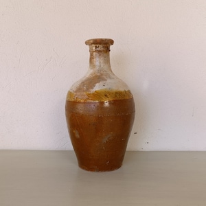 May include: A brown ceramic bottle with a white glaze and a yellow band around the middle. The bottle has a rounded body and a narrow neck.