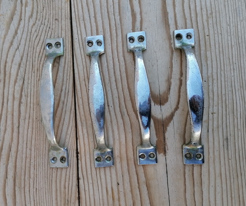 May include: Four silver door handles with a polished finish. The handles have a simple, rectangular design with rounded edges.