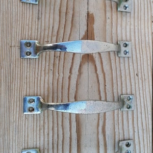 May include: Four silver cabinet door handles with a brushed finish. The handles are in a row on a wooden surface.
