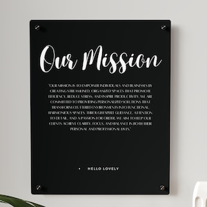 May include: Black and white sign with the text "Our Mission" and a description of the company's mission to empower individuals and businesses by creating streamlined, organized spaces that promote efficiency, reduce stress, and inspire productivity. The sign also includes the text "Hello Lovely" at the bottom.