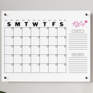May include: White dry-erase calendar with a black grid and text. The months of the year are listed across the top, and the days of the week are listed below. There is a to-do list and a "Don't Forget" section on the right side of the calendar. The name "Kylie" is written in pink cursive with a pink heart next to it.