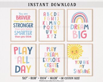May include: Six wall art prints featuring pastel-colored typography and graphics. Designs include an alphabet, a rainbow with the text DREAM BIG, a sun with YOU ARE MY SUNSHINE, and motivational phrases like PLAY ALL DAY and YOU ARE BRAVER.