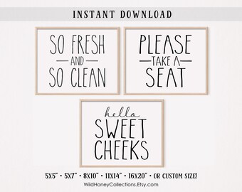 May include: Three framed wall art prints with black text on a white background. The prints read "SO FRESH AND SO CLEAN", "PLEASE TAKE A SEAT", and "hello SWEET CHEEKS". The frames are a light wood color.