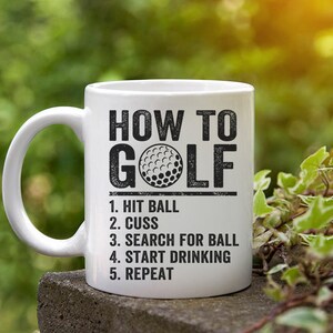Pu&ograve; includere: Una tazza da caff&egrave; in ceramica bianca con una grafica nera che dice "How to Golf" e elenca i passaggi: "1. Hit Ball, 2. Cuss, 3. Search for Ball, 4. Start Drinking, 5. Repeat".
