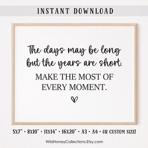 Puede incluir: Una impresión enmarcada con el texto "The days may be long but the years are short. Make the most of every moment." La impresión está en un marco de madera clara e incluye un símbolo de corazón. Los tamaños disponibles son 12.7x17.8cm, 20.3x25.4cm, 28x35.6cm, 40.6x50.8cm, A3, A4 o tamaño personalizado.