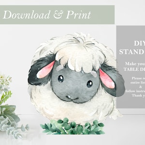 May include: Printable DIY stand-up sheep with watercolor style illustration. The sheep has a white fluffy body, black face, and pink ears. The sheep is standing on a bed of green leaves. The text "DIY STAND UPS! Make your own TABLE DECOR! Please read entire listing & follow instructions. Thank you!" is in the background.