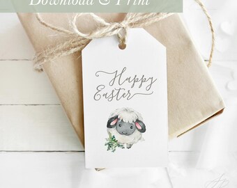 Op de afbeelding: Een wit, printbaar cadeau-etiket met de tekst "Happy Easter" in cursief schrift. Onder de tekst staat een aquarel-illustratie van een wit schaap met zwarte ogen en hoeven. Het etiket is vastgebonden aan een bruine papieren cadeauzak met touw.