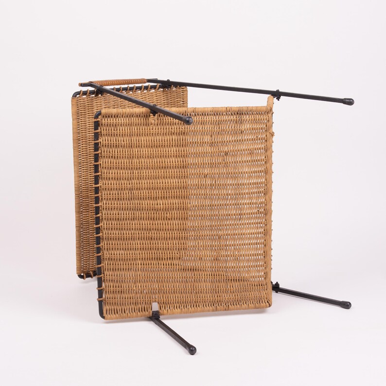 May include: A woven wicker room divider with a rectangular shape. The divider has a light brown color and is supported by black metal legs and a frame. The design is simple and functional, suitable for various interior styles.