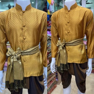May include: A gold long-sleeved shirt with a patterned design and a matching pair of pants. The shirt has a mandarin collar and a button-up front. The pants are a traditional style with a wide leg.