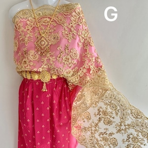May include: A pink and gold traditional Thai dress with intricate lace detailing. The dress features a gold belt and a gold necklace.