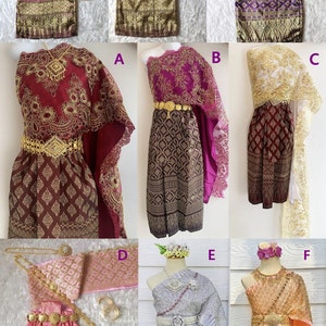 May include: Six different traditional Thai outfits for girls, each with a different colour scheme and design. The outfits include a long skirt, a top, and a sash. Some outfits also include a shawl or a necklace.