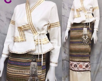 May include: White long-sleeved blouse with gold trim and a wrap-style closure. The blouse is paired with a brown and white striped skirt with a silver pendant.
