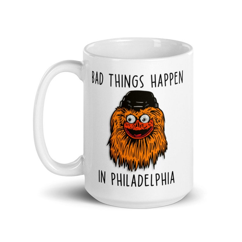 May include: White ceramic mug with a black and orange illustration of the Philadelphia Flyers mascot, Gritty, wearing a black hat. The text "Bad things happen in Philadelphia" is printed on the mug.