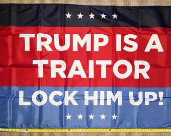 May include: A red, white, and blue flag with the text "TRUMP IS A TRAITOR LOCK HIM UP!" printed in white. There are five white stars in the top black stripe and five white stars in the bottom blue stripe.