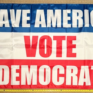 May include: A blue, white, and red flag with the text "SAVE AMERICA VOTE DEMOCRAT" printed in white letters.