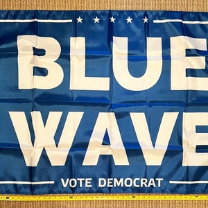 May include: A blue flag with white text that reads "BLUE WAVE VOTE DEMOCRAT".