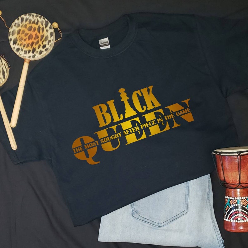 May include: Black t-shirt with gold text that reads "Black Queen" and "The Most Sought After Piece In The Game".