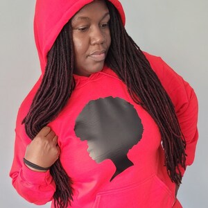 May include: A red hooded sweatshirt with a black silhouette of a woman with an afro on the front.