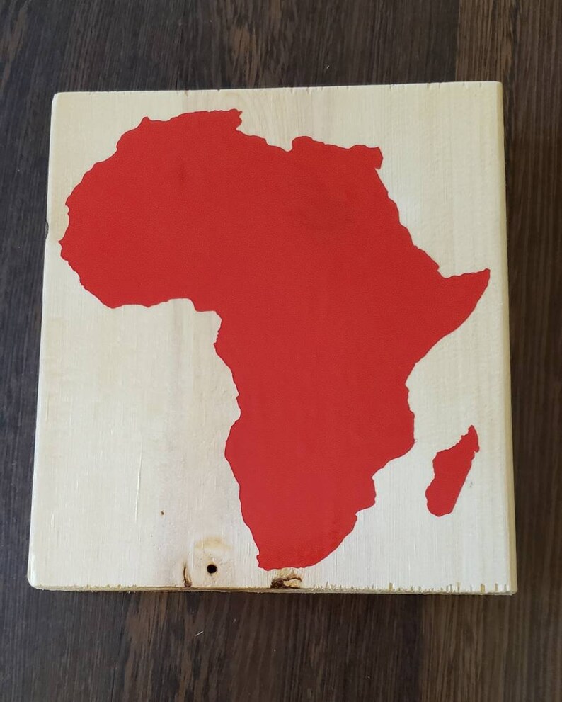 May include: A red painted wooden sign with the outline of the continent of Africa.