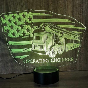 May include: A green 3D printed night light shaped like a concrete pump truck with an American flag in the background. The text "OPERATING ENGINEER" is printed below the truck.