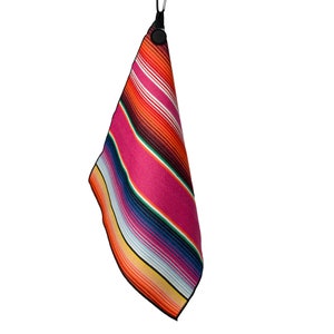 May include: A colorful striped towel with a bright pink background and orange, yellow, blue, and white stripes. The towel is hanging from a black clip.