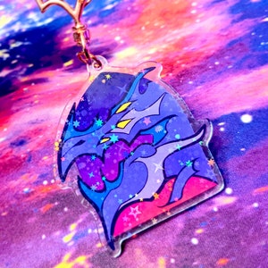 May include: A holographic charm featuring a blue and purple dragon with a star-shaped design. The charm is made of clear acrylic and has a glittery finish.