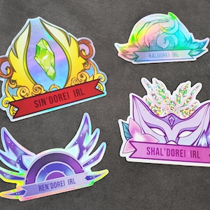 May include: Four iridescent stickers with different designs. Each sticker features a different color scheme and a banner with the text "D'OREI IRL" and a different word before it. The stickers are on a dark gray surface.