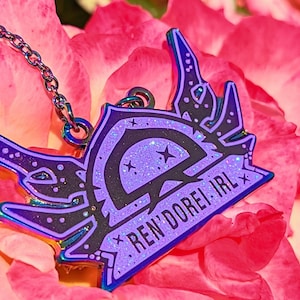May include: A iridescent purple and black enamel pin with a crescent moon and stars design. The pin has the text "Ren'dorei IRL" on it and is attached to a silver chain.