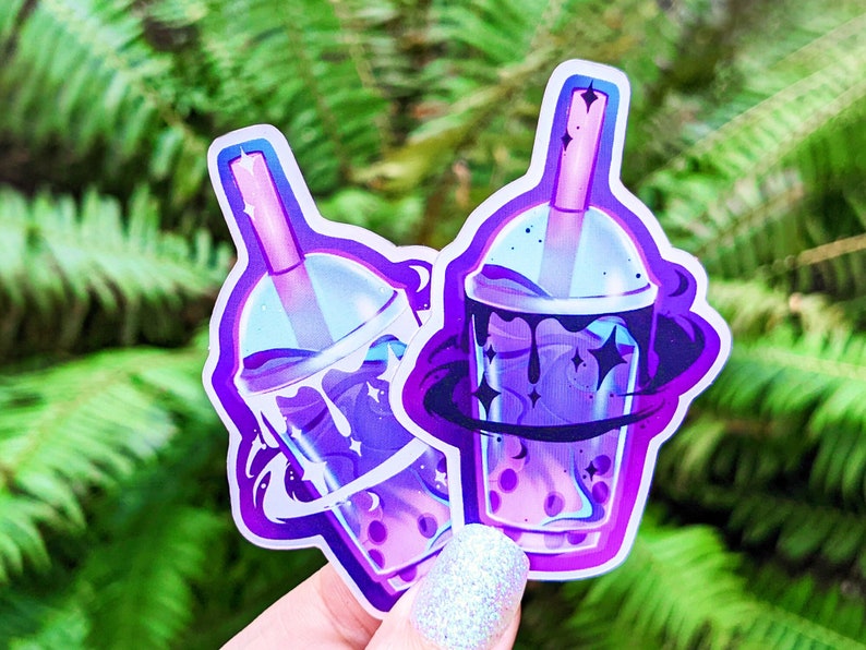 May include: Two purple and blue galaxy themed bubble tea stickers with a swirling galaxy design and stars. The stickers are on a white background.